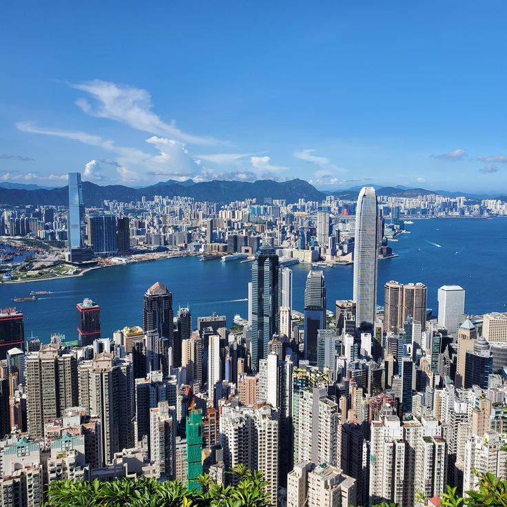 Aerial view of Hong Kong skyline and Victoria Harbour under a clear blue sky
