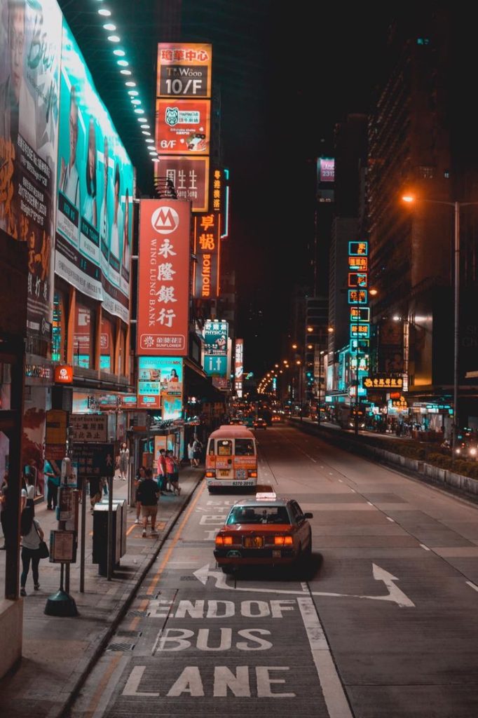 Busy Hong Kong street at night with neon signs, taxis, and buses in Mong Kok